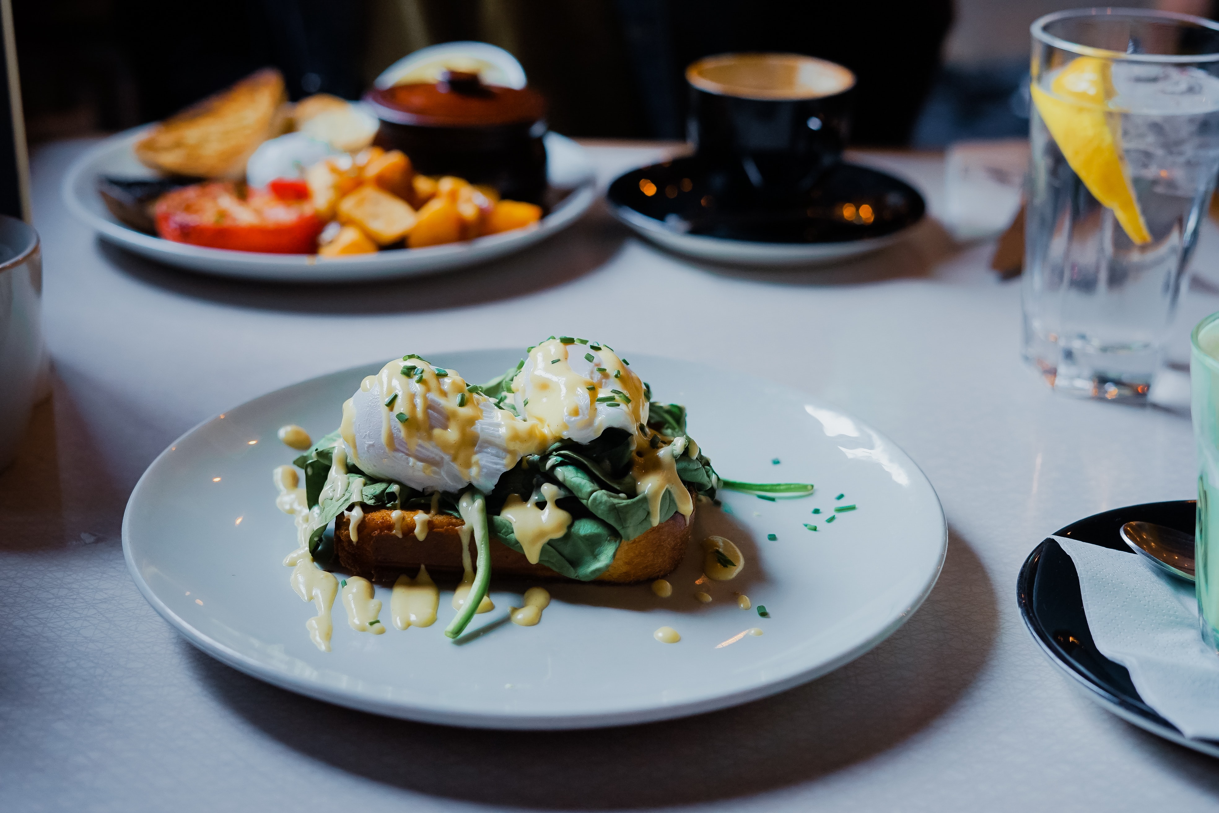 poached eggs on top of spinach and toast with Hollandaise sauce on a white plate